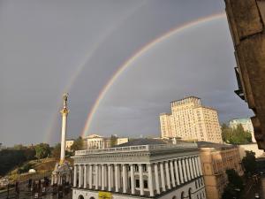 a rainbow in the sky over a city with a building at Майдан in Kyiv