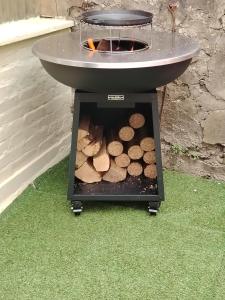 a barbecue grill with a pile of fire logs at studio neuf in Beaumont-sur-Oise