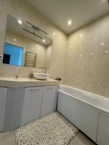 a bathroom with a sink and a tub and a mirror at Panorama Apartment in Lviv +4 photos