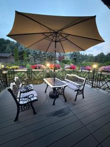 a patio with two chairs and a table and an umbrella at Apartamenty Anielski Sen 3 in Świeradów-Zdrój
