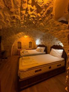 two beds in a room in a stone cave at Ayataç Konak Otel in Urfa