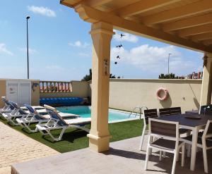 a patio with chairs and a table and a pool at Casa Lily in Caleta De Fuste