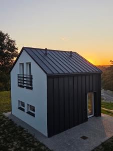 a black and white building with a sunset in the background at Sonińskie Wzgórze Domki 