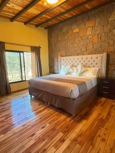 a bedroom with a large bed with a stone wall at Lujo Rustico Lago Cerca Terraza Mascotas in Llano Grande