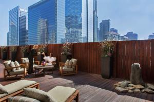 a woman standing on a rooftop patio with chairs and tables at InterContinental Toronto Centre by IHG in Toronto