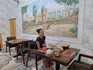 a woman sitting at a table in a restaurant at Sobirjon Guest House in Khiva