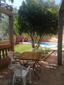 a wooden table and chairs on a patio with a tree at Aberge Tigmenon Ouirgane in Ouirgane +9 photos