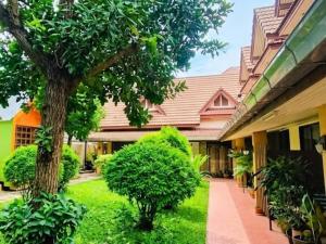 a courtyard of a building with a tree and grass at สวนไมตรีจิต รีสอร์ท Suan Maitrichit Resort in Ban Khlong Si