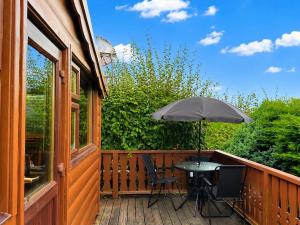 a table and two chairs on a deck with an umbrella at Snowdonia Escape in Trawsfynydd