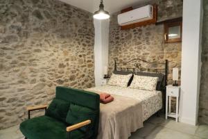 a bedroom with a bed and a green chair at Casa Loma Lola in Molinaseca