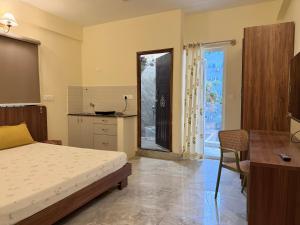 a bedroom with a bed and a desk and a kitchen at Namma HomeSlice, Balcony Rooms in Brookefield in Bangalore