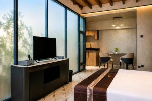 a bedroom with a bed and a tv and a table at TUNA Hiriketiya - Luxury Resort & Pool Retreat in Hiriketiya