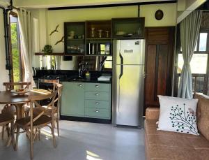 a kitchen with a refrigerator and a table with chairs at Cabana Flamboyant in Praia Grande
