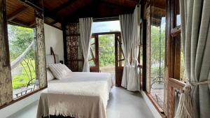 a bedroom with a bed in a room with windows at Cabana Flamboyant in Praia Grande