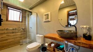 a bathroom with a sink and a toilet and a mirror at Cabana Flamboyant in Praia Grande