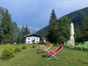 a group of lawn chairs and an umbrella and a house at Albergo Scoiattolo Dolomites Experience in Falcade