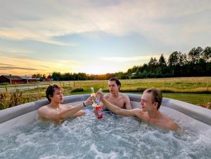 a group of three men drinking beer in a bathtub at Kolsta Gård 
