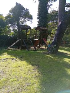a park with a playground and a tree at la Casita del bosque in Villa Gesell