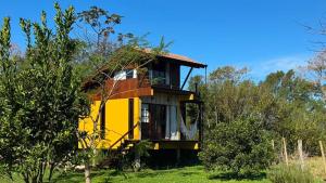 a yellow house in the middle of a field at Cabana Flamboyant in Praia Grande