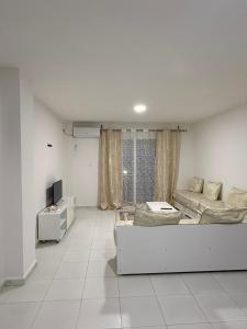 a white living room with a couch and a tv at Résidence assia in Jijel