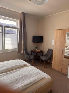 a bedroom with a bed and two chairs and a television at Pension Haus Beckmann in Borkum