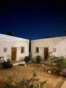 a white building with two doors and some plants at La Bohème - Chambres d'hôtes in Midoun
