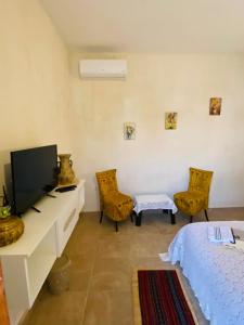 a bedroom with a tv and a bed and chairs at La Bohème - Chambres d'hôtes in Midoun