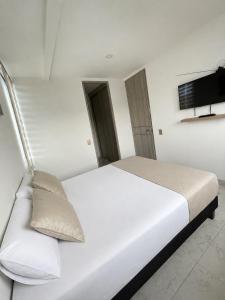 a bedroom with a white bed and a tv at Suite Vista Azul Ricaurte in Ricaurte +16 photos
