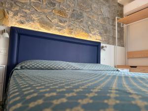 a blue bed in a room with a stone wall at Cinquestelle Albergo del centro storico in Palinuro +124 photos