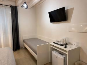a small room with a bed and a tv on the wall at Le Quattro Porte in Marsala