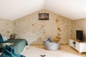 a bedroom with a bed and a tv on a wall at La borderie de Beauregard in Treize-Vents