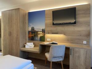 a bedroom with a desk with a television on a wall at Hotel & Restaurant Lenzer Krug in Malchow