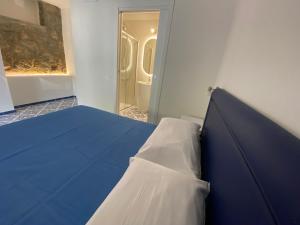 a blue bed in a room with a door at Cinquestelle Albergo del centro storico in Palinuro