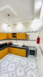 a kitchen with yellow cabinets and a stove at Residence ADN Walo in Richard Toll