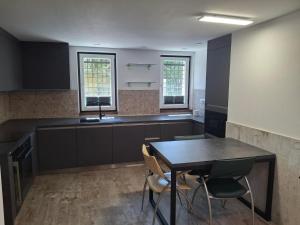 a kitchen with black cabinets and a table and chairs at Apartmán Palza Jablonec in Jablonec nad Nisou