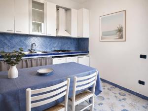 a kitchen with a blue table and white cabinets at Maridea - La Marina in Ponza +3 photos