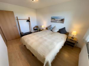 a bedroom with a large white bed and two lamps at Kleine Hérrlichkeit 22 in Wangerland