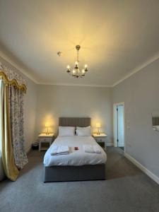 a bedroom with a large bed and two tables and a chandelier at Edinburgh West Residences in Edinburgh