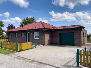 a small red brick house with a green garage at Kleine Hérrlichkeit 22 in Wangerland