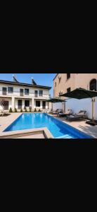 a large swimming pool with chairs and an umbrella at Barseghyans Villa in Nor-Kesariya