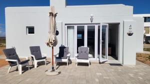 a group of chairs and an umbrella on a patio at Ocean Whisper Strandfontein in Strandfontein