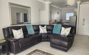 a brown leather couch in a living room at Ocean Whisper Strandfontein in Strandfontein