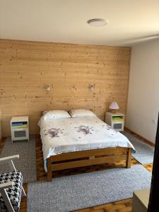 a bedroom with a bed with a wooden wall at Apartmani Zelena jela in Šljivovica