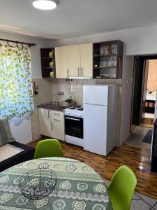 a kitchen with a table and a white refrigerator at Apartmani Zelena jela in Šljivovica
