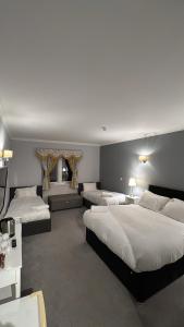 a hotel room with three beds and a television at Edinburgh West Residences in Edinburgh