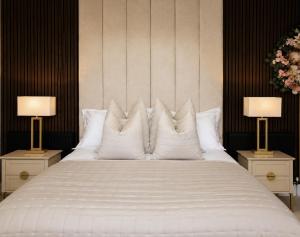 a large bed with white pillows and two lamps at Cedar House at The Old Fire Station in Canterbury