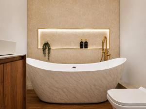 a bathroom with a tub and a toilet at Cedar House at The Old Fire Station in Canterbury