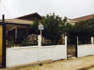 a white fence in front of a house with a sign at Bello Horizonte in El Quisco