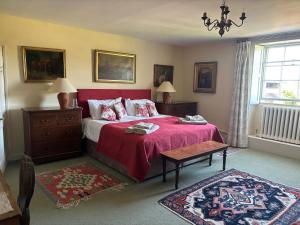 a bedroom with a large bed with a red blanket at Crudwell House in Crudwell