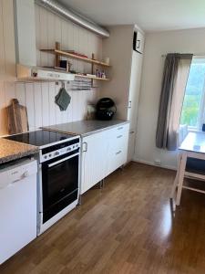a kitchen with white cabinets and a stove top oven at Midtigården in Teksdal